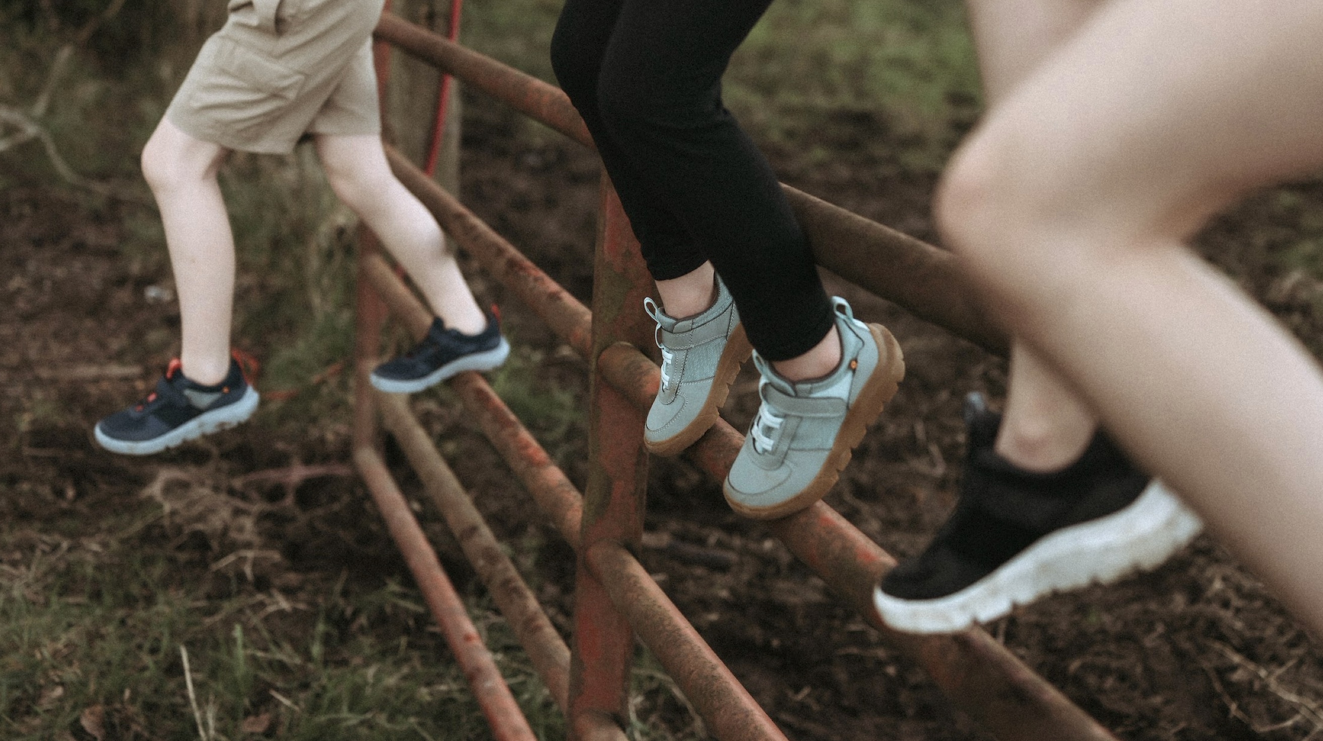 Click to shop the Kids Skyline Kicker featuring kids sitting on an old gate.