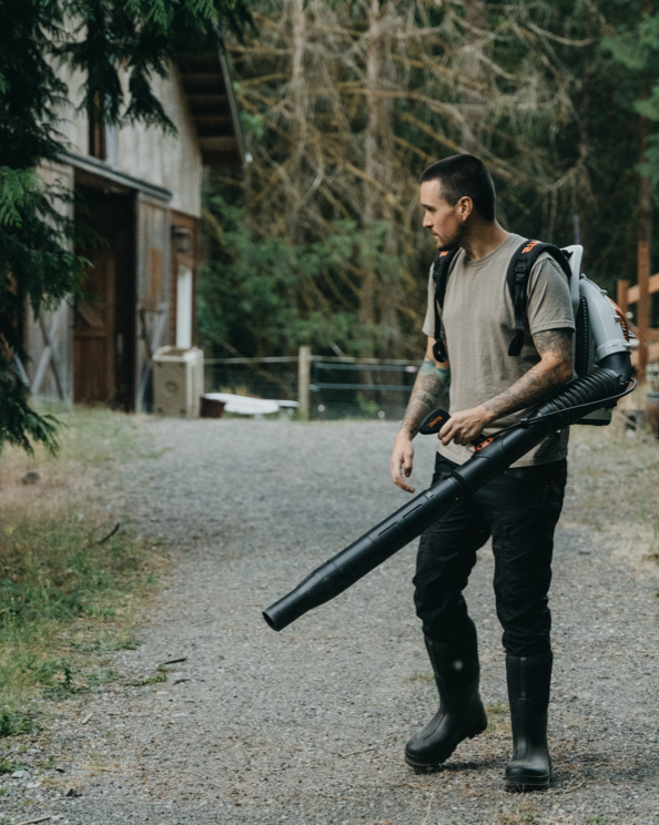 Click to shop the men's Rancher featuring a man with a leaf blower. 