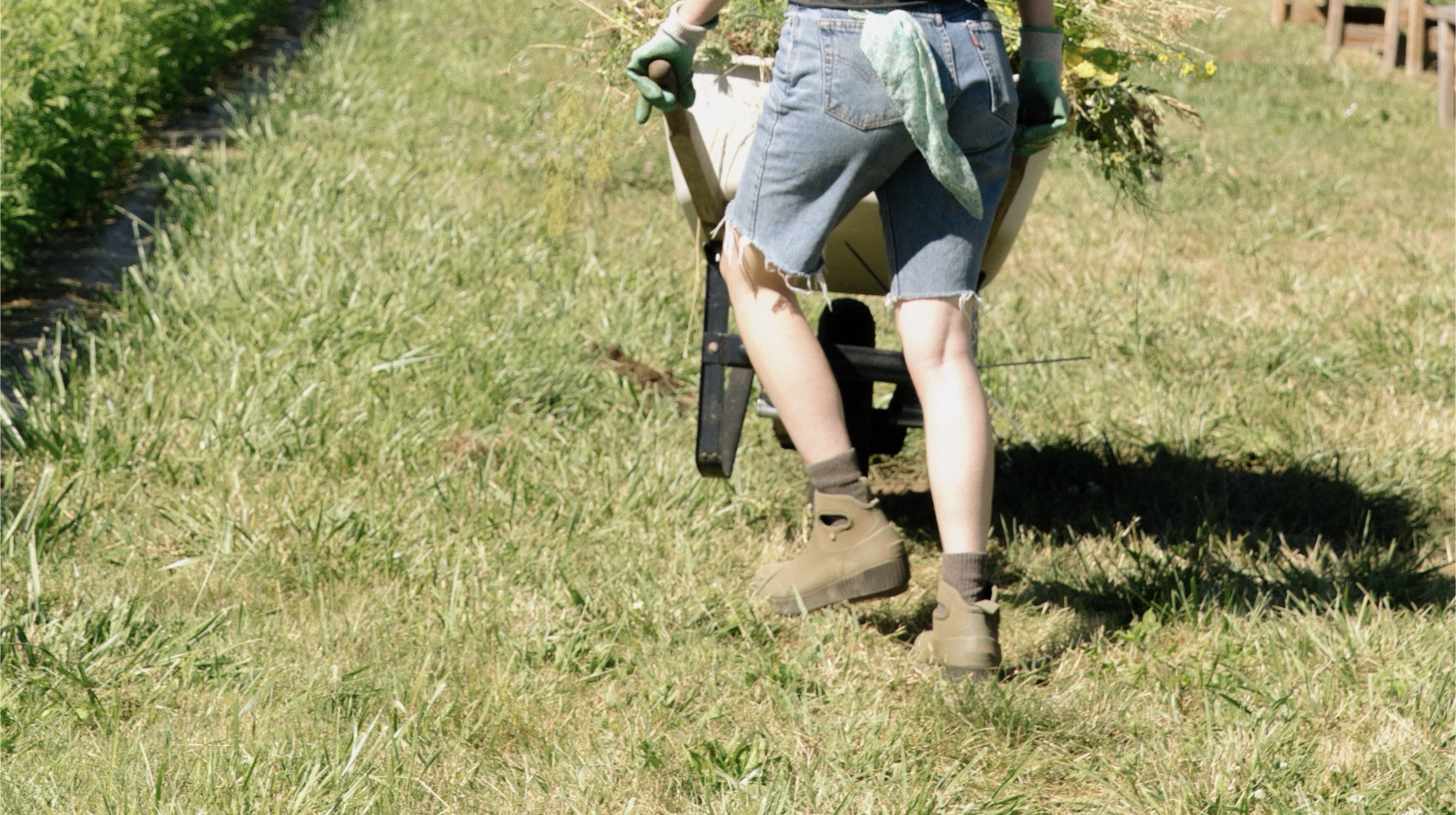 Click to shop the women's Seattle II featuring a women pushing a wheelbarrow.