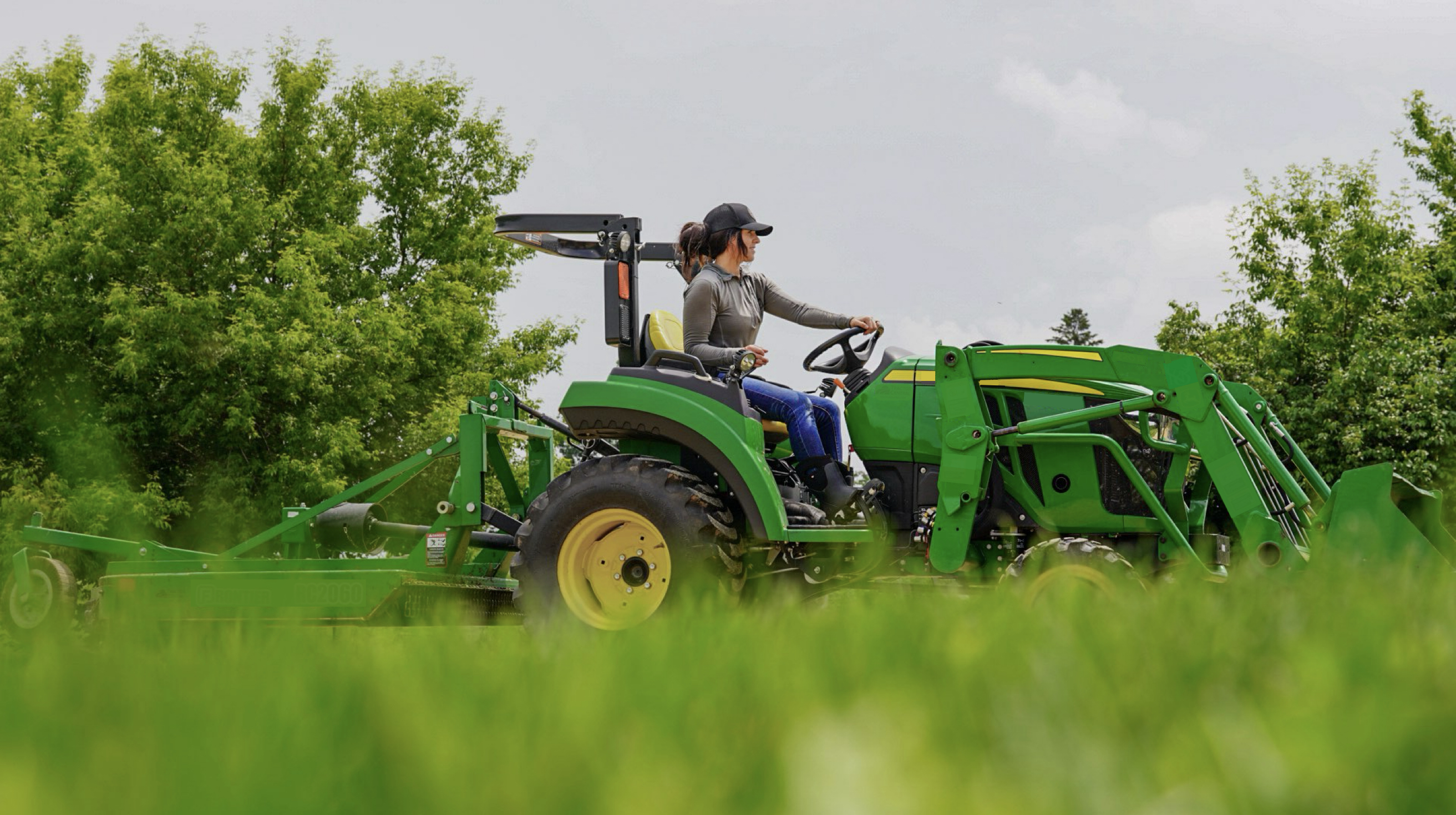 A woman riding a tractor.  Shop our Women's Farm & Work boots.