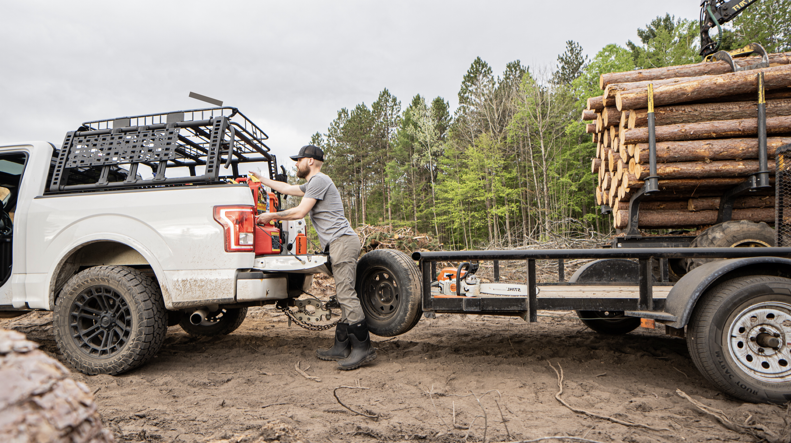 A guy pulling out of heavy equipment out of a truck with a trailer of logs. Shop our Men's Classic Seamless boots in black