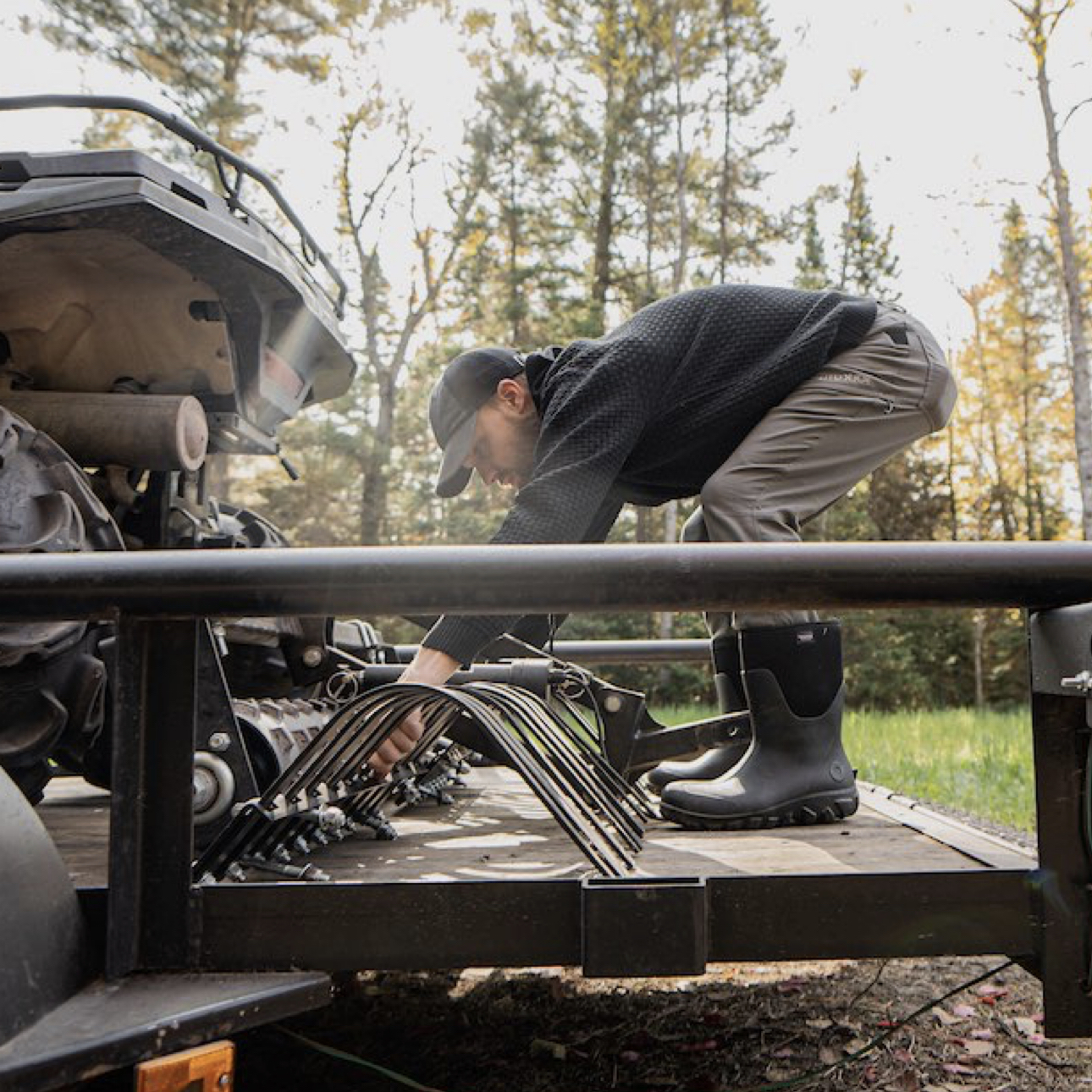 A man gearing a metal grate from the back of his truck.  Shop our Men's work boots.