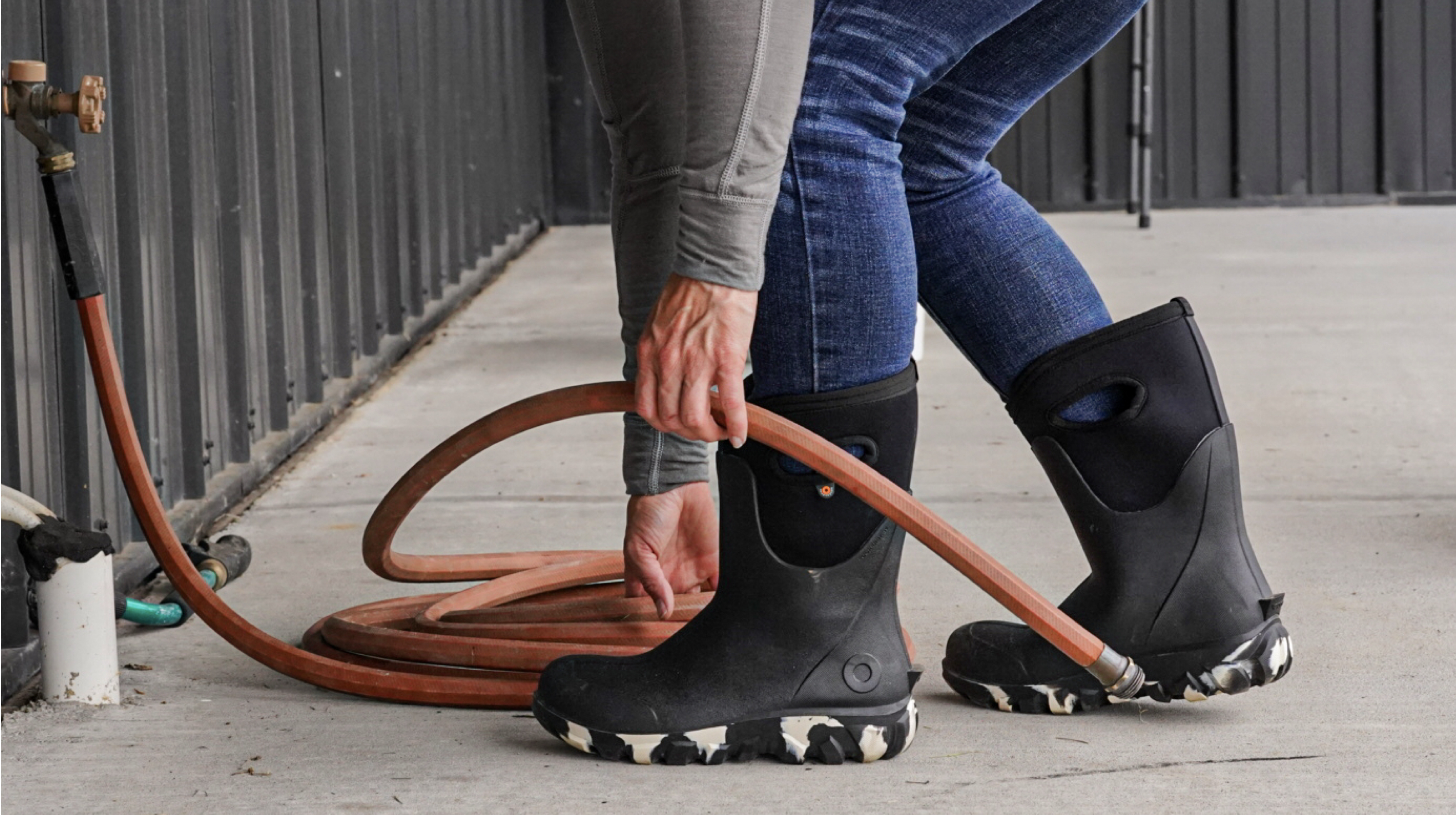A waist down image of a woman picking up a hose wearing the new Women's Seamless classic boots.