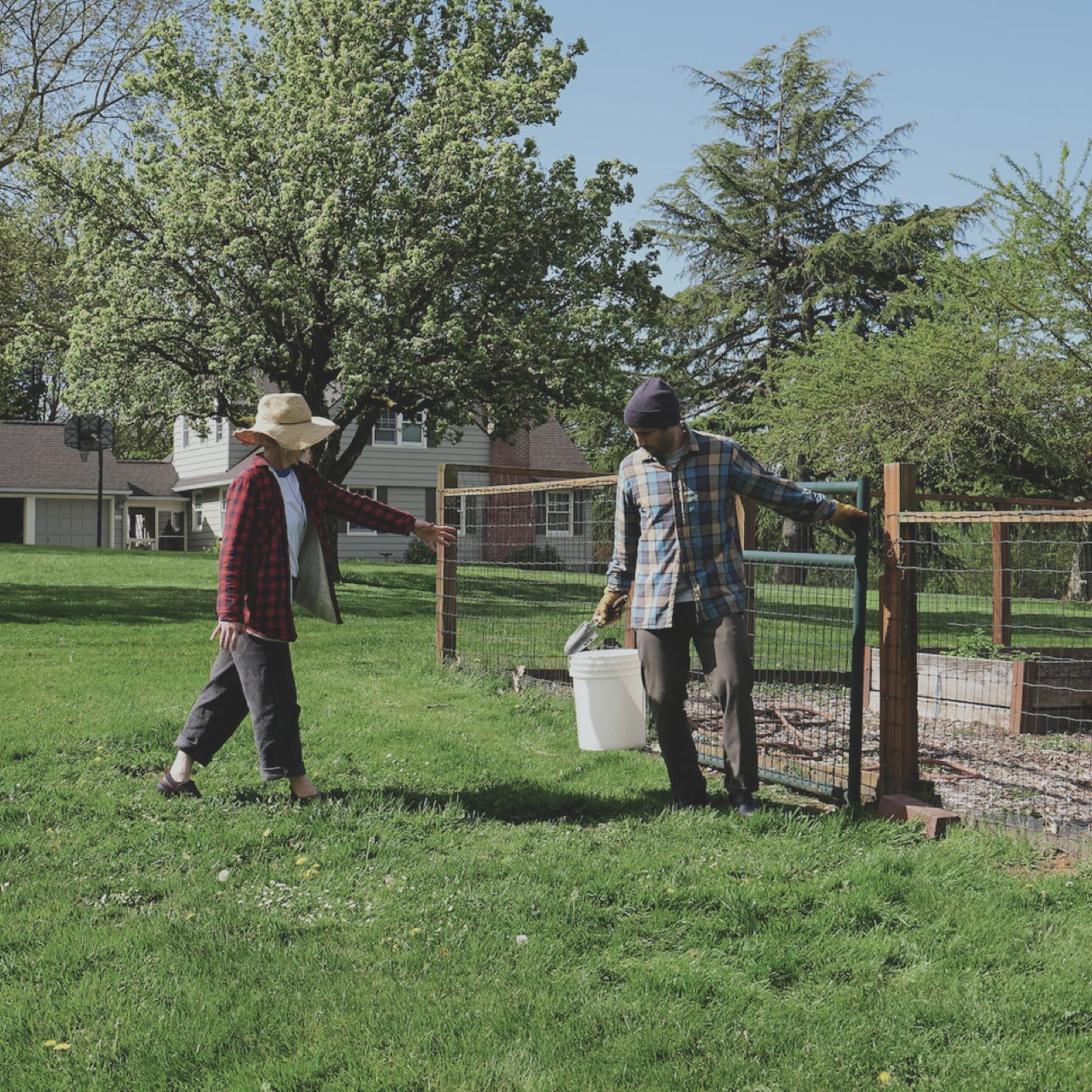 A guy handing a white bucket to a woman in a field. Shop our recommended fall chore boots.