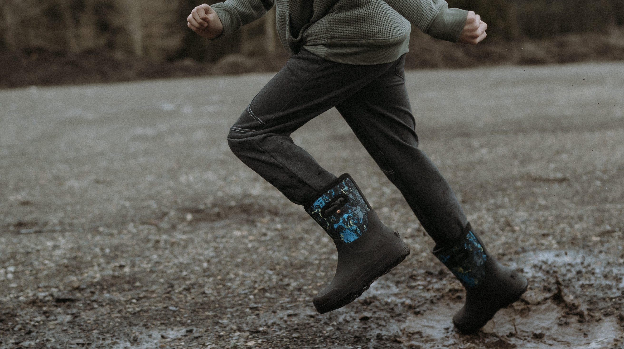 A waist shot image of a kid splashing through a puddle wearing our new York seamless.
