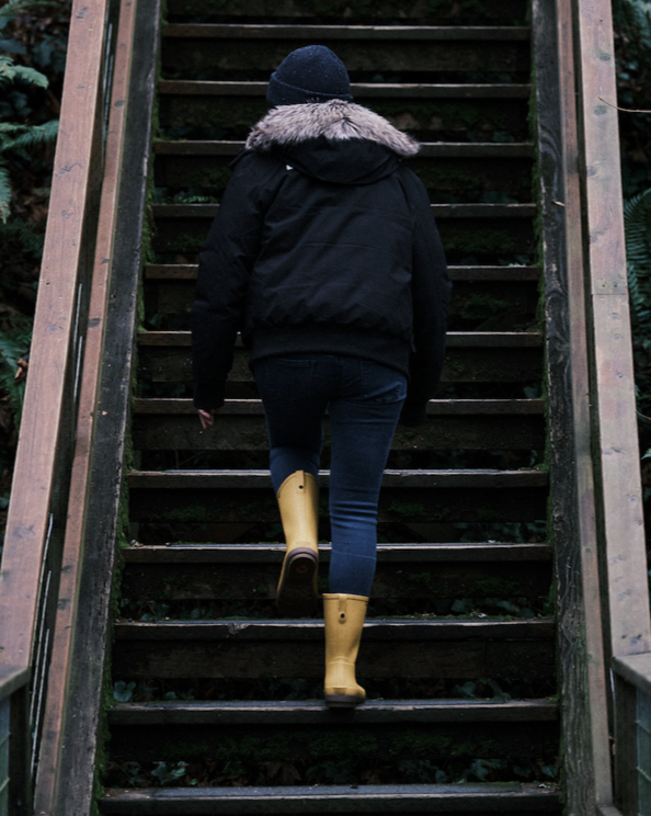 A woman walking up a staircase in the woods, wearing the Amanda II Mid in yellow