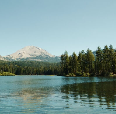 Click here to learn more about our eco initiatives and what we are doing to decrease our bootprint. The picture shown is a nature landscape with a mountain, trees & lake.