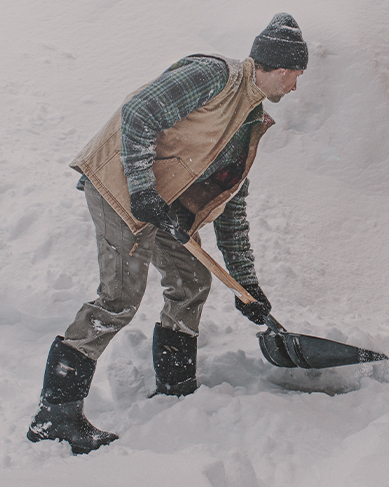Shop men's winter boots featuring a man shoveling snow.