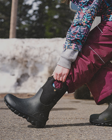 Shop kids' Classic Seamless featuring a kid putting on their boots in the parking lot.