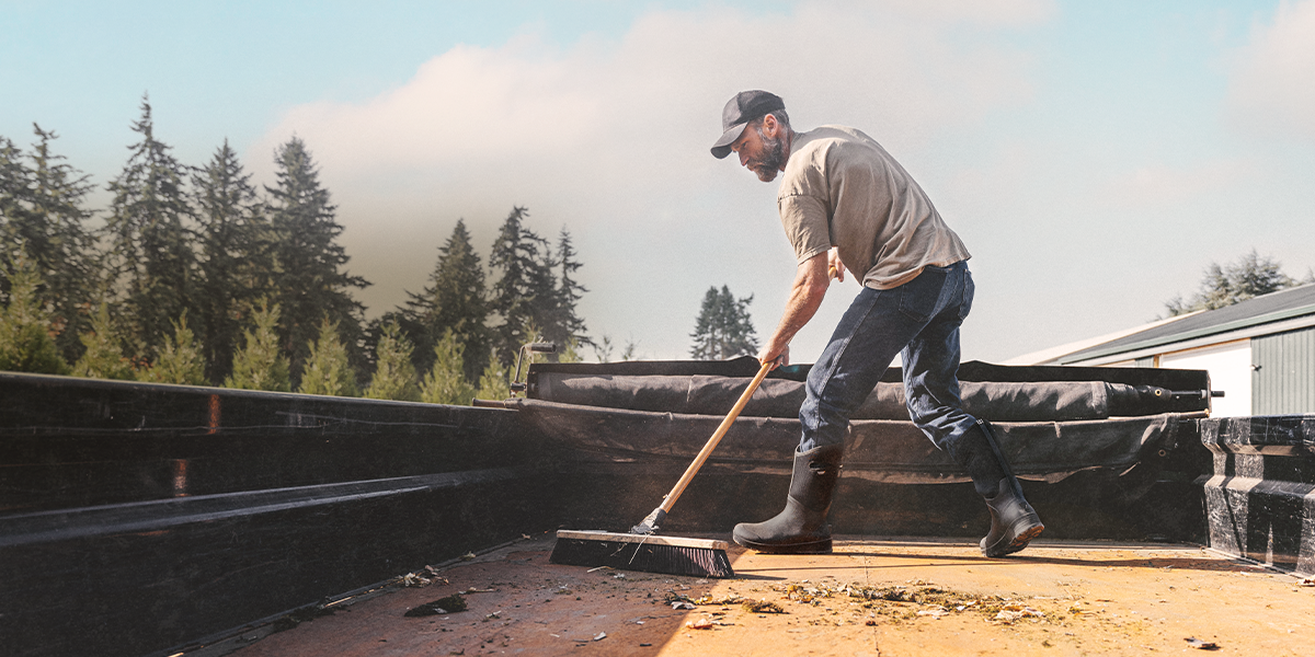 Shop the men's Bozeman II featuring a man sweeping out a truck bed.