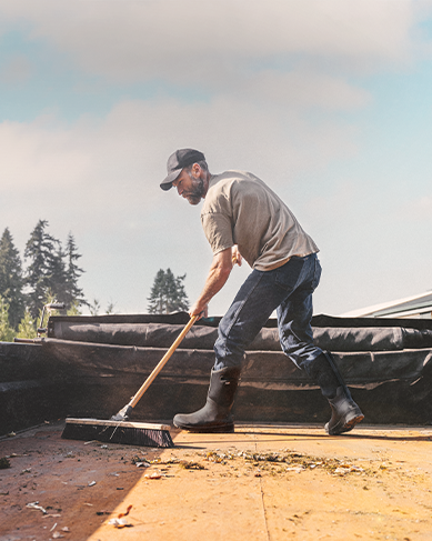 Shop the men's Bozeman II featuring a man sweeping out a truck bed.