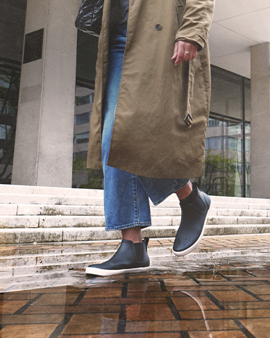 Shop women's fall essentials featuring a woman walking in the rain.