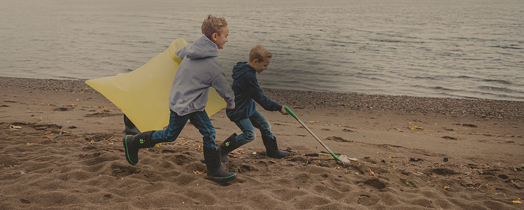 Shop Bogs kids' featuring 2 boys playing on a beach. 