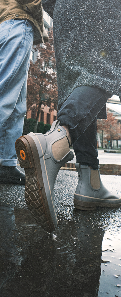 Unisex Neo-Tech graphic. Image features a model walking in a puddle wearing BOGS Neo-Tech waterproof boots.