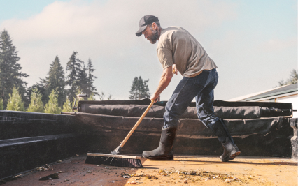 Image features a man sweeping dust and                leaves off the back of a truckbed while wearing BOGS Classic Seamless boots in black.