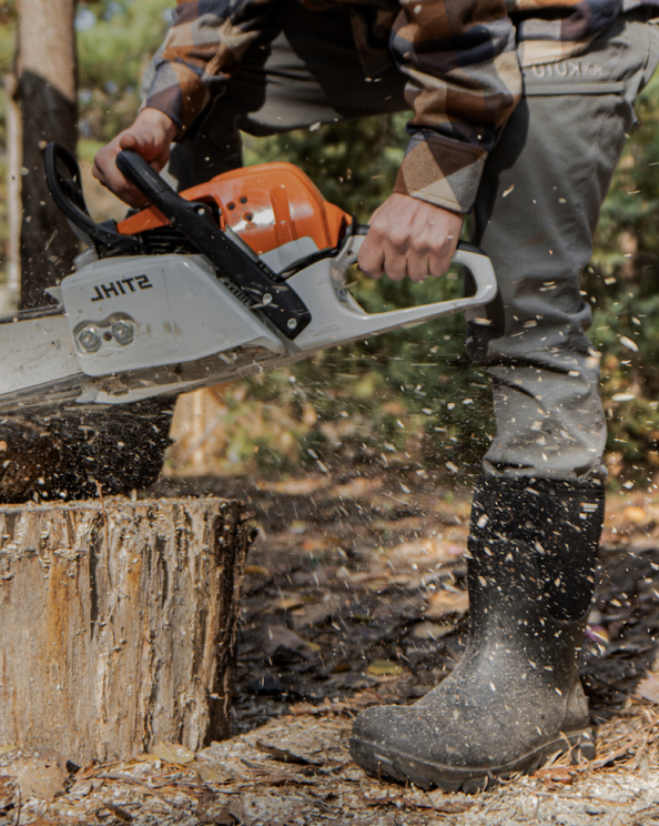A man chopping wood with a chainsaw wearing the Men’s Classic Seamless mid work boots