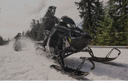 For the Outdoor Enthusiast. Image shows a person on a snowmobile driving through snow with Bogs on.