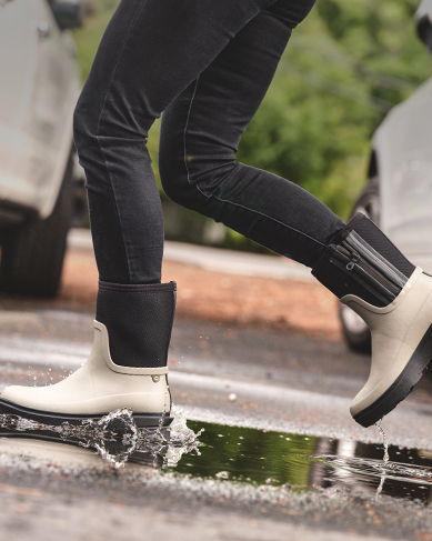 Image features the Hazel Mid Zip in taupe walking through a puddle.