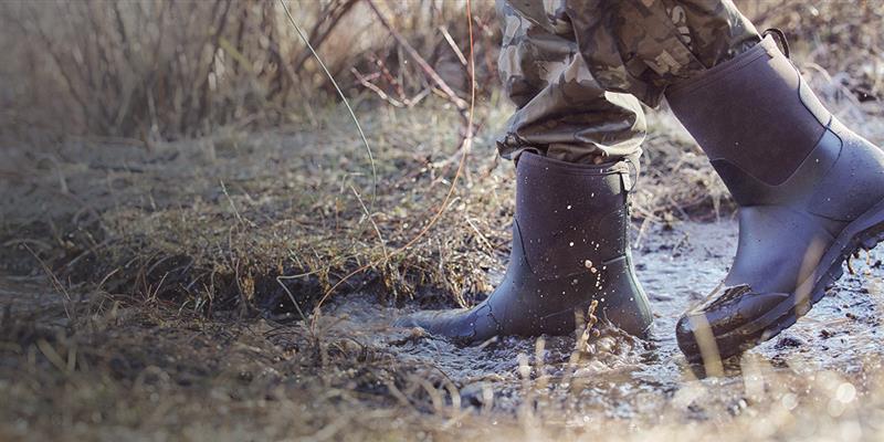 Image features a man walking through a muddy puddle.