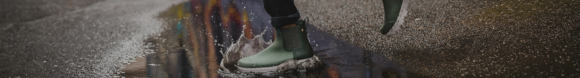 Image features a woman walking through a puddle in green boots. 