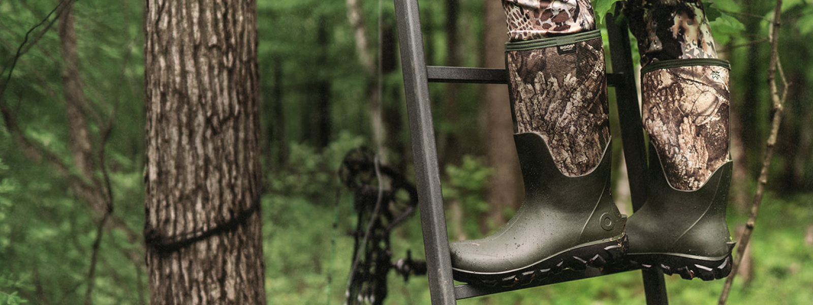 Shop the Classic Seamless Tall in Realtree APX camo. Image shows a man standing in a tree stand wearing his Classic Seamless Realtree APX in the woods.