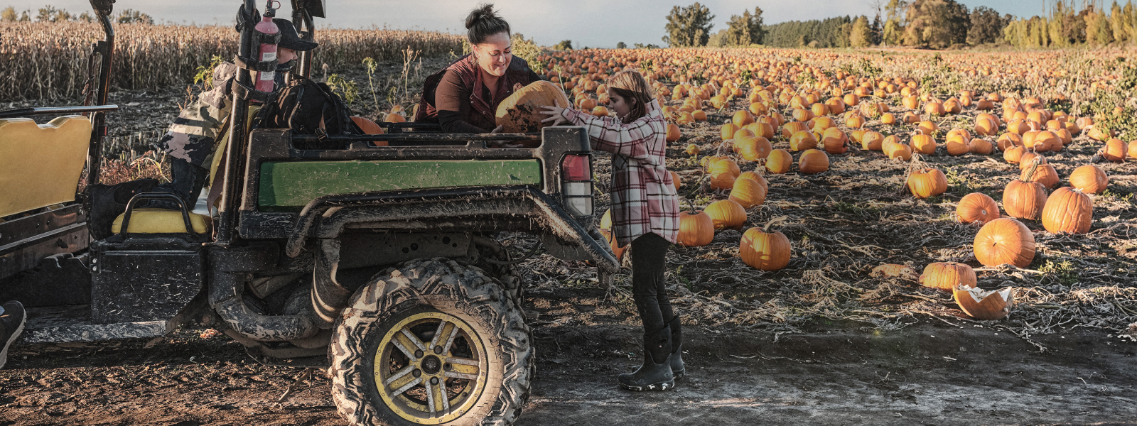 Shop our fall clearance Event with 20% off all clearance items using code FALL26. Image shows a women and her daughter in a pumpkin patch wearing their BOGS while picking up a pumpkin.