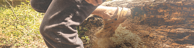 Image features a close-up of a model stepping down through a dusty,                grassy path while wearing the BOGA Unisex Casual Slip On in the color Sahara.