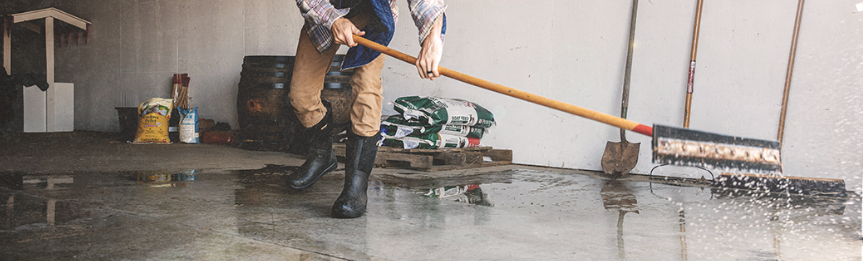 Image features the Bozeman II tall boot with a man sweeping water out of his garage.