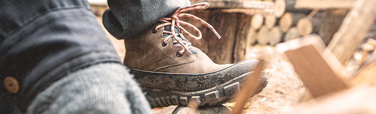 Image shows a close up of BOGS lace-up boot                 being propped up on a log outside.